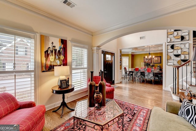 living room featuring ornamental molding, arched walkways, visible vents, and stairs