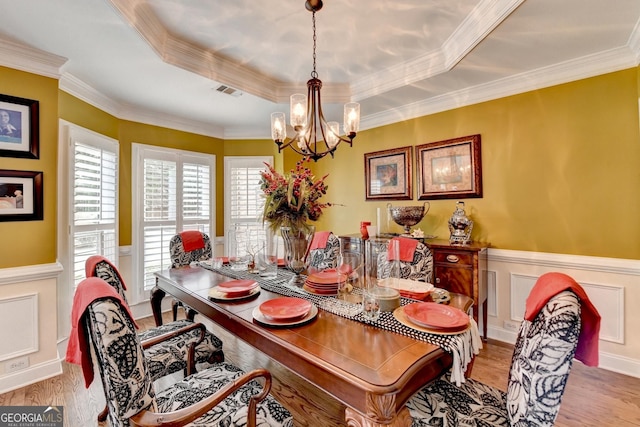 dining room featuring a raised ceiling, visible vents, a notable chandelier, and wainscoting