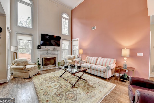 living room featuring visible vents, ornamental molding, a wealth of natural light, and wood finished floors