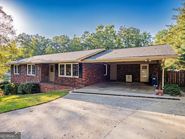 ranch-style home with a carport, brick siding, driveway, and fence