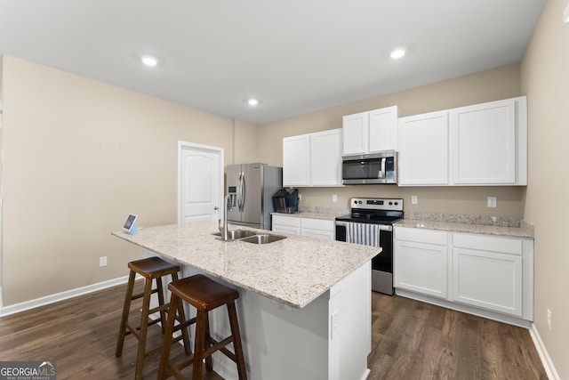 kitchen with white cabinets, a center island with sink, stainless steel appliances, and dark wood finished floors