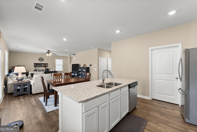 kitchen featuring stainless steel appliances, dark wood-style flooring, a sink, visible vents, and light stone countertops