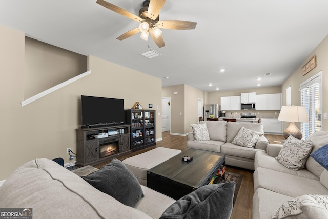 living room featuring recessed lighting, baseboards, wood finished floors, and a glass covered fireplace