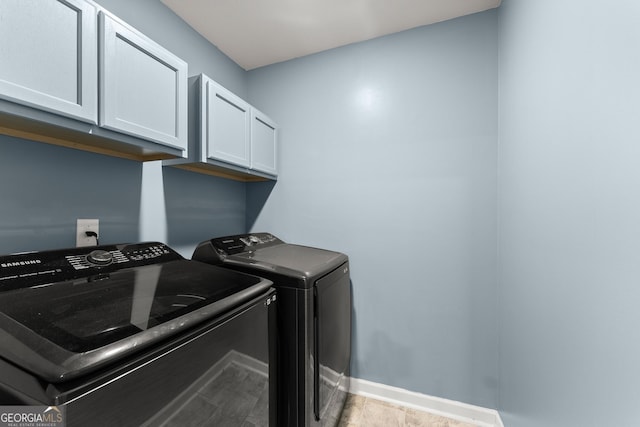 clothes washing area with washer and clothes dryer, wood finished floors, cabinet space, and baseboards