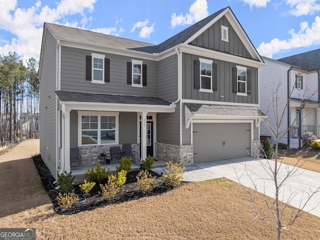 view of front of property featuring covered porch, a garage, brick siding, concrete driveway, and board and batten siding