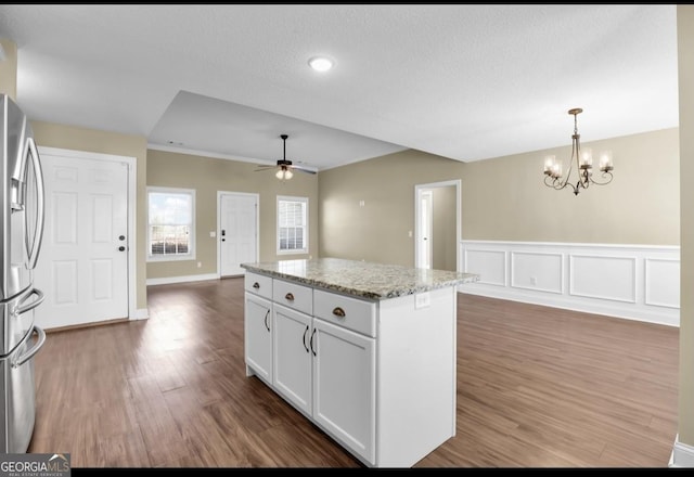 kitchen featuring white cabinets, stainless steel fridge with ice dispenser, a kitchen island, open floor plan, and wood finished floors