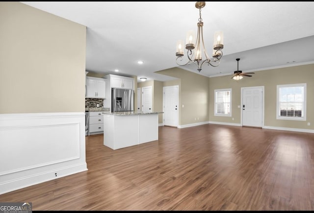 unfurnished living room with ornamental molding, dark wood finished floors, baseboards, and ceiling fan with notable chandelier