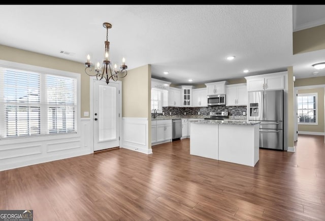 kitchen featuring stainless steel appliances, dark wood-type flooring, white cabinetry, a kitchen island, and a sink