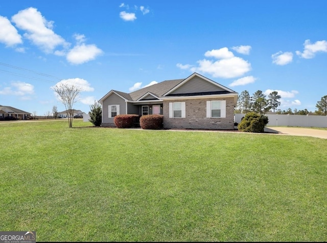 ranch-style home with brick siding, a front yard, and fence