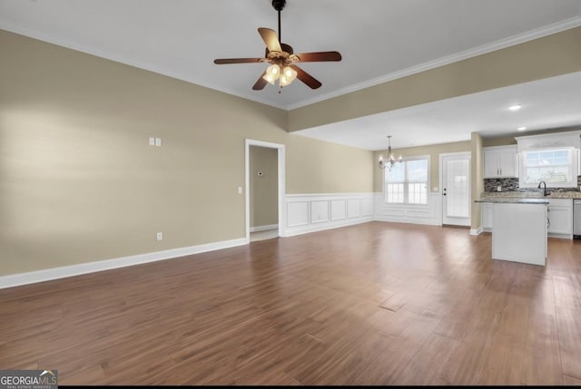 unfurnished living room featuring ornamental molding, dark wood finished floors, a sink, and ceiling fan with notable chandelier