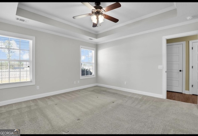 unfurnished room with carpet floors, a tray ceiling, visible vents, and crown molding