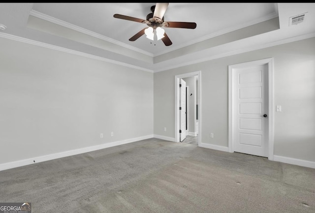 carpeted spare room featuring a tray ceiling, visible vents, crown molding, and baseboards