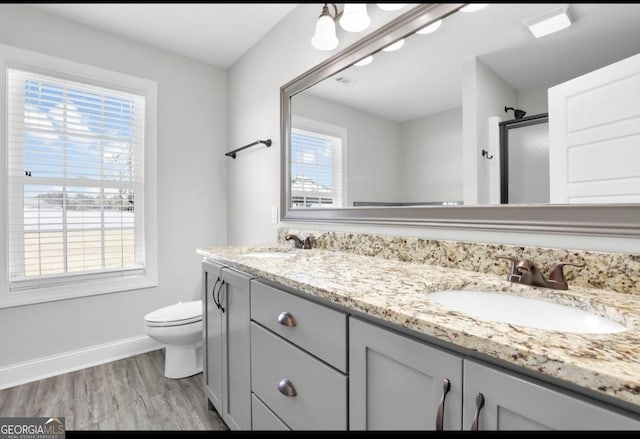 bathroom featuring double vanity, a stall shower, a sink, and toilet