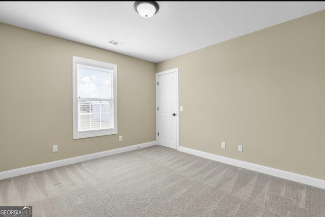 carpeted spare room featuring baseboards and visible vents