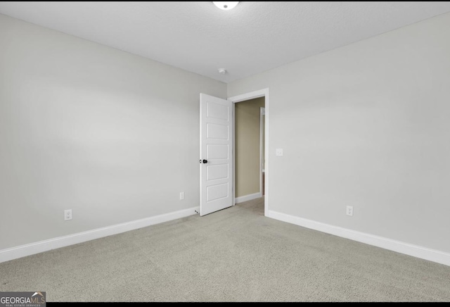 carpeted empty room featuring a textured ceiling and baseboards