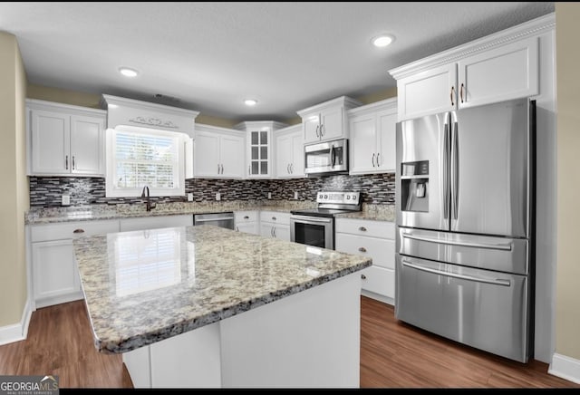 kitchen with white cabinetry, appliances with stainless steel finishes, tasteful backsplash, and dark wood-type flooring