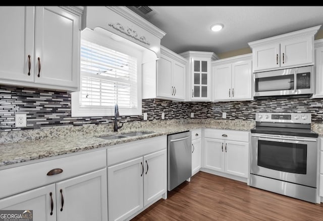 kitchen featuring stainless steel appliances, glass insert cabinets, white cabinets, a sink, and wood finished floors