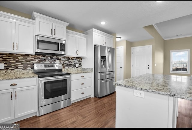 kitchen featuring tasteful backsplash, white cabinets, dark wood finished floors, ornamental molding, and stainless steel appliances