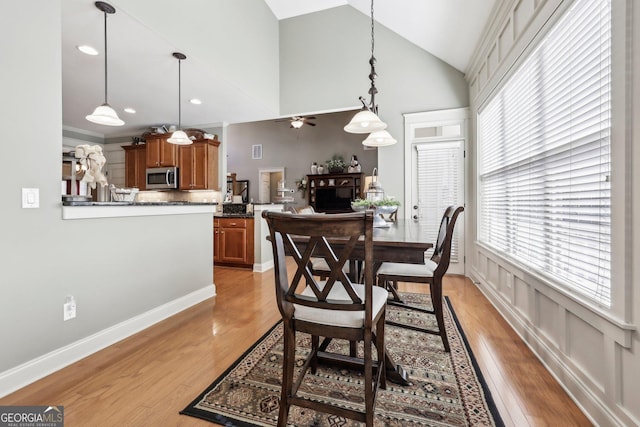 dining area with recessed lighting, light wood-style flooring, ceiling fan, high vaulted ceiling, and baseboards