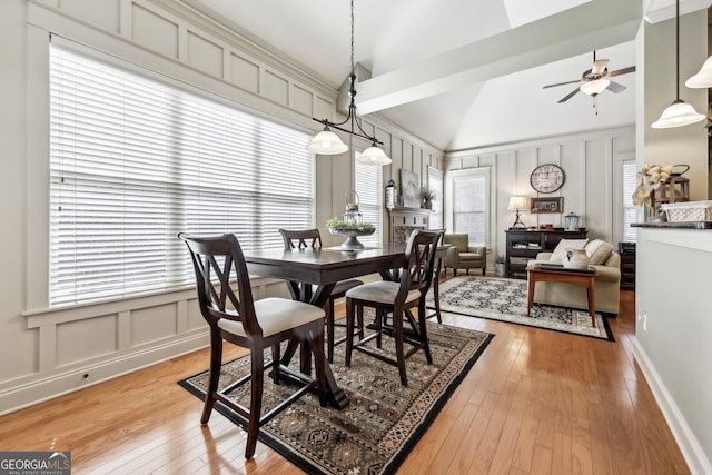 dining space with lofted ceiling, a ceiling fan, light wood-style flooring, and a decorative wall