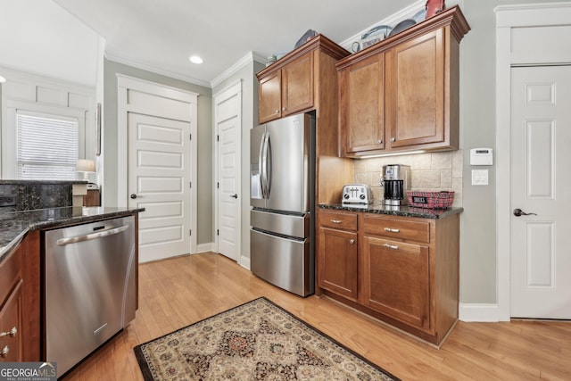 kitchen featuring brown cabinets, crown molding, tasteful backsplash, appliances with stainless steel finishes, and light wood-type flooring