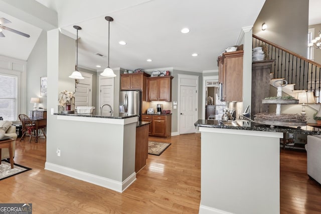 kitchen with light wood-style flooring, ornamental molding, brown cabinets, a peninsula, and stainless steel refrigerator with ice dispenser