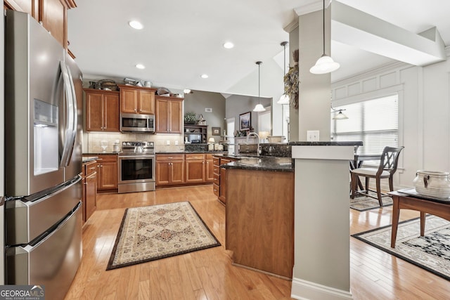 kitchen with a peninsula, light wood-style floors, appliances with stainless steel finishes, and brown cabinetry