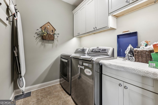 clothes washing area with baseboards, cabinet space, and washer and dryer