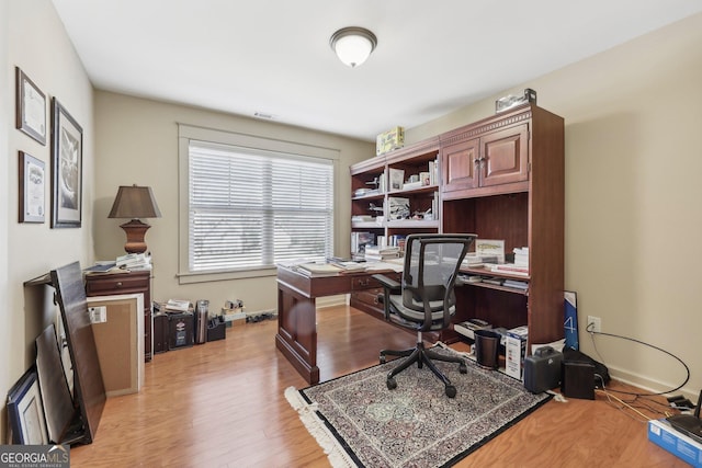 office space with baseboards, visible vents, and light wood finished floors