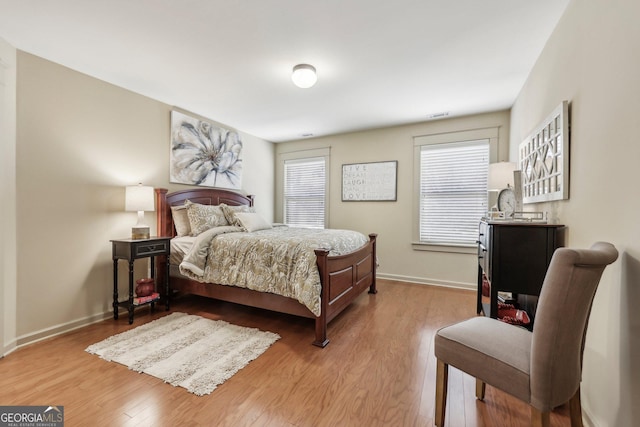 bedroom featuring light wood finished floors, visible vents, and baseboards