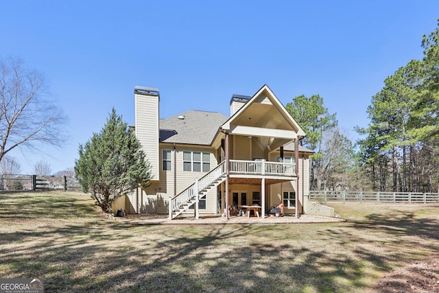 rear view of property with a chimney, stairway, a patio area, fence, and a deck