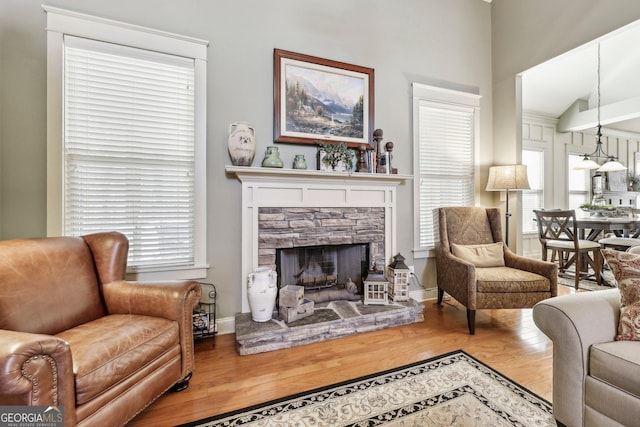 living area with plenty of natural light, a fireplace, baseboards, and wood finished floors