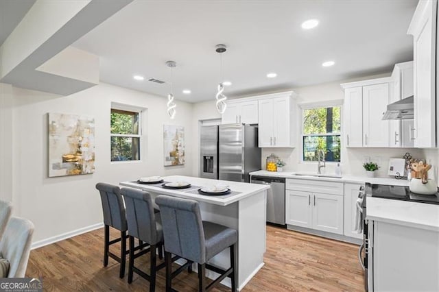 1270 Graymont Dr, Atlanta, GA 30310 - kitchen featuring white cabinets, appliances with stainless steel finishes, under cabinet range hood, a sink, and a center island