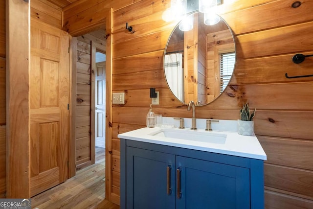 bathroom with wood walls, vanity, and wood finished floors