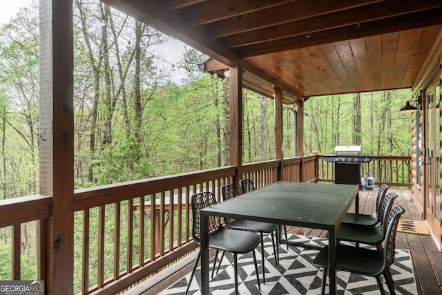 wooden deck featuring outdoor dining space and a view of trees