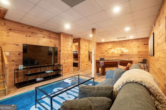 living room featuring a paneled ceiling, wooden walls, and wood finished floors