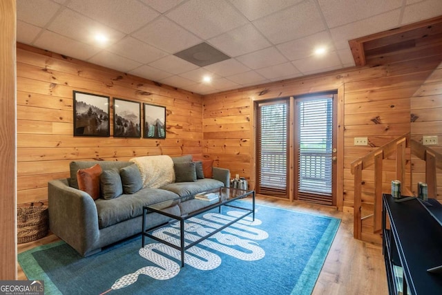 living room featuring a paneled ceiling, wood walls, and wood finished floors