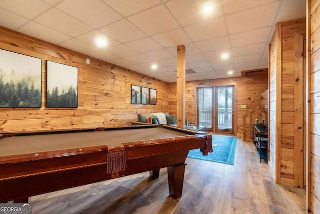 rec room with billiards, wooden walls, a drop ceiling, and wood finished floors