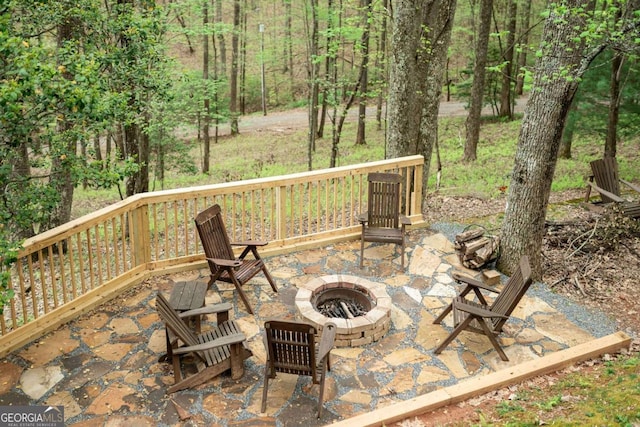 view of patio / terrace featuring an outdoor fire pit and a view of trees