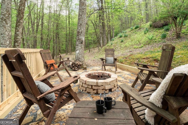 view of patio / terrace with a fire pit and a view of trees