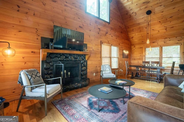 living area with high vaulted ceiling, a fireplace, wood walls, and wood finished floors