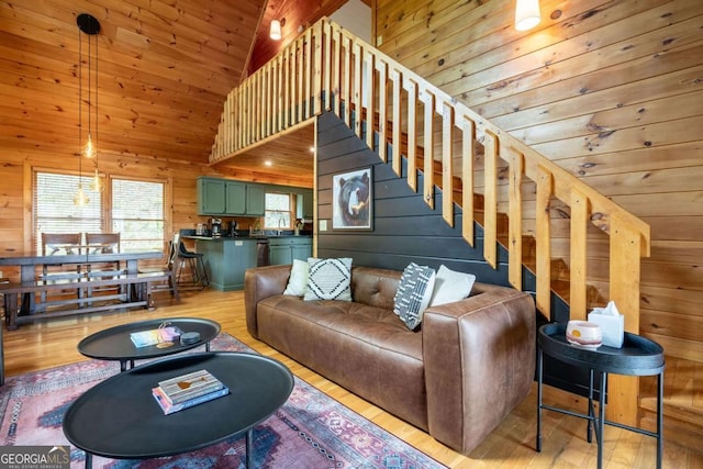 living area with wood ceiling, wood walls, light wood-style flooring, and stairway