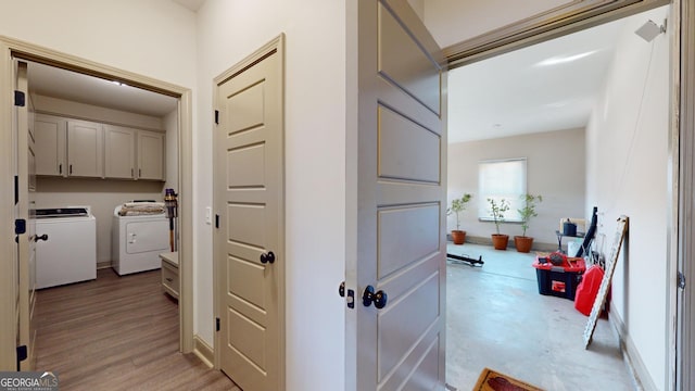 hall featuring light wood finished floors, washing machine and dryer, and baseboards