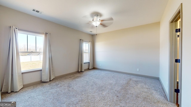 unfurnished room with carpet floors, ceiling fan, visible vents, and baseboards