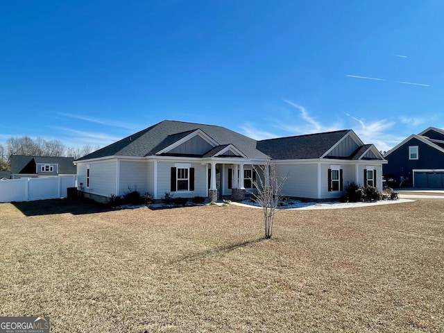 view of front of property with board and batten siding, fence, and a front lawn