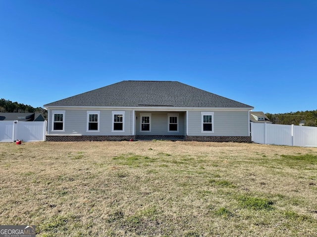 back of house featuring a shingled roof, a lawn, and a fenced backyard