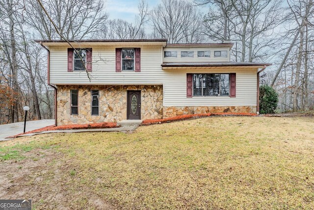 split level home featuring stone siding and a front yard