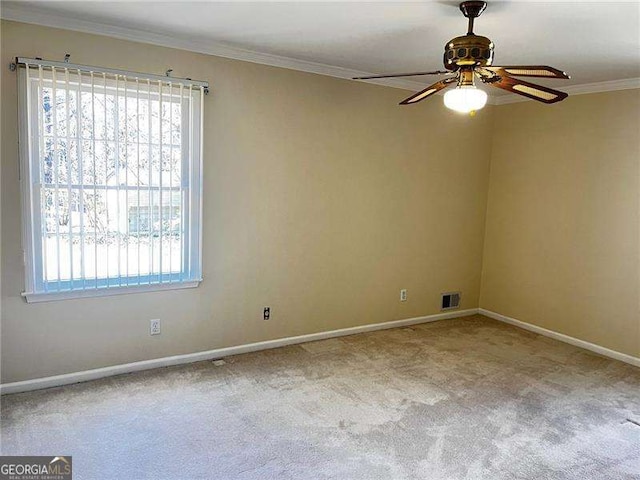 carpeted spare room with baseboards, visible vents, ceiling fan, and ornamental molding