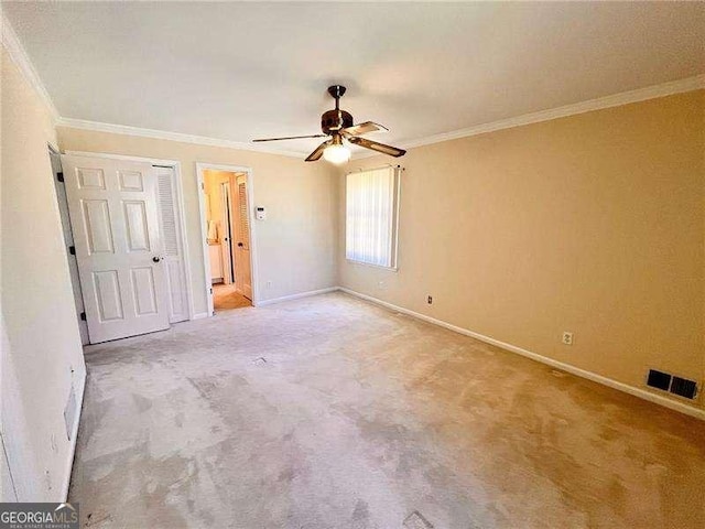 unfurnished bedroom with baseboards, light carpet, visible vents, and crown molding