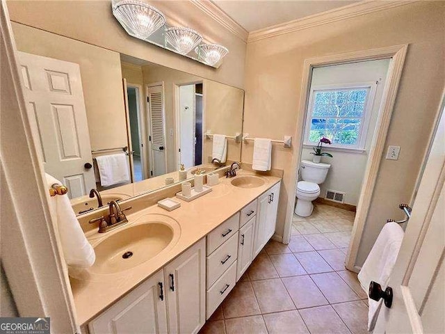 bathroom featuring toilet, ornamental molding, a sink, and visible vents